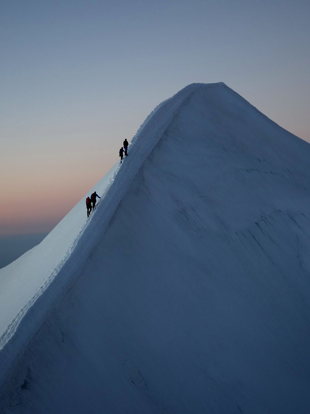 Montaña nevada y dos montañeros subiendo a la cima