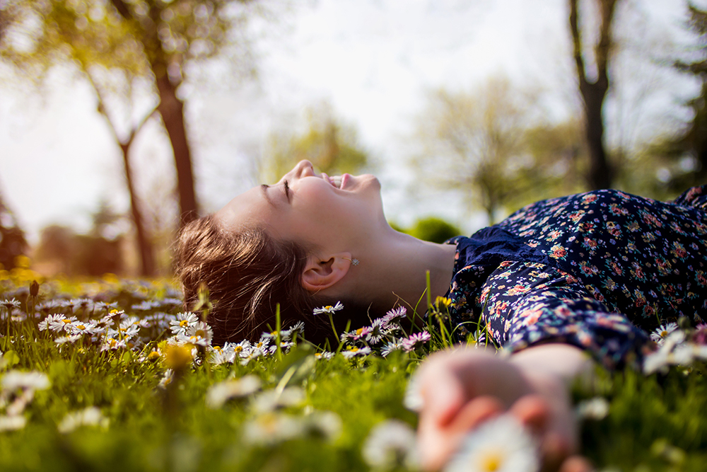 chica tumbada boca arriba en la hierba,  paisaje de primavera